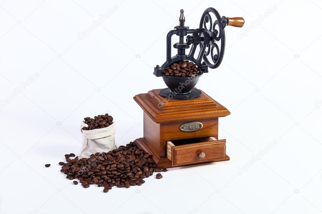 an old hand grinder for grinding coffee beans, roasted coffee beans on a white background.