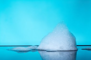 Foam, bubbles with reflection on dark glass, blue background clipart