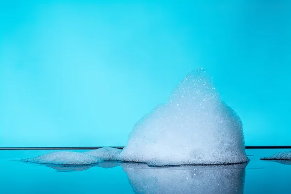 Mousse, bulles avec réflexion sur verre foncé, fond bleu — Photo