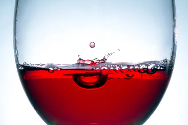 Red wine in glass, splashing, splash, bubbles, drops of wine close up