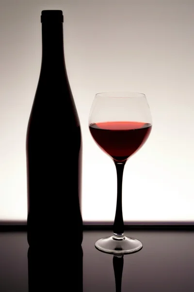 Silhouette di una bottiglia di vino con bicchiere con vino rosso — Foto Stock