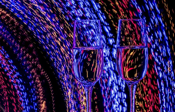 Zwei Gläser Champagner auf einem Hintergrund abstrakter farbiger Lichter in Bewegung — Stockfoto