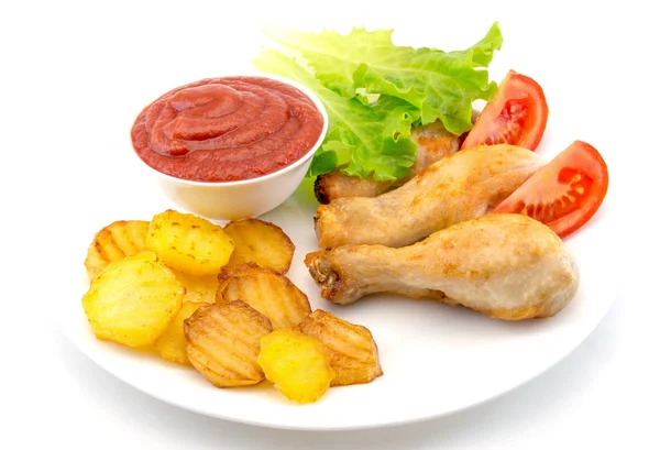 Chicken legs on a white plate with slices of tomato and lettuce and french fries and ketchup top view isolated — Stock Photo, Image
