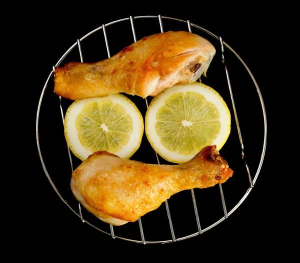 Patas de pollo en la parrilla con rodajas de limón aisladas sobre fondo negro —  Fotos de Stock