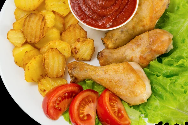 Patas de pollo frito en un plato blanco con rodajas de tomate y lechuga y papas fritas y salsa de tomate vista superior aislado —  Fotos de Stock