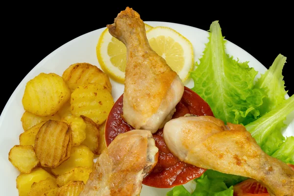 Patas de pollo en un plato blanco con rodajas de tomate y lechuga y papas fritas y salsa de tomate vista superior aislado —  Fotos de Stock
