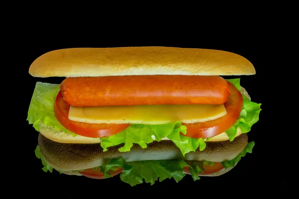 Hot dog with fresh leaf lettuce and two slices of tomato with reflection isolated on a black background — Stock Photo, Image