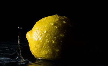 Limonlu suda ıslatın ve siyah arka plan üzerine damla su sıçramalarına gelen yansıma 