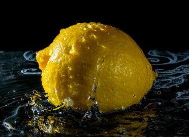 Limonlu suda ıslatın ve siyah arka plan üzerine damla su sıçramalarına gelen yansıma 