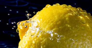 Yakın limon kadar su sıçramalarına koyu arka plan üzerinde damla