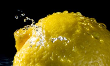 Yakın limon kadar su sıçramalarına koyu arka plan üzerinde damla