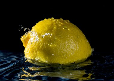 Limonlu suda ıslatın ve siyah arka plan üzerine damla su sıçramalarına gelen yansıma 