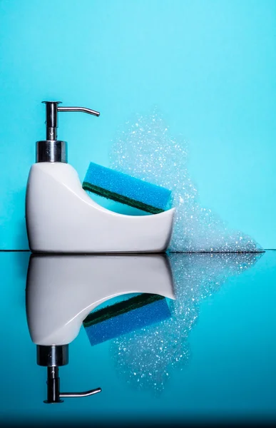 Pequeño baño con esponja y espuma con reflejo sobre fondo azul, detergente — Foto de Stock