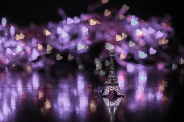 Miniatur-Eiffelturm Silhouette kleine Schlüssel auf dem Schlüsselanhänger mit einem Spiegelbild auf dem Hintergrund Bokeh in Form von bunten Herzen — Stockfoto