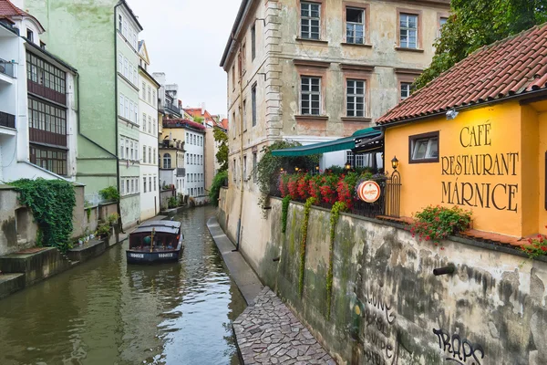 Prague, Czech Republic - 17 August, 2015: Boat on the canal in Prague on a day near the house and a cafe on the waterfront. — Stock Photo, Image