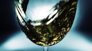 Bir bardağa dökülen beyaz şarabın yaratıcı makro yavaş çekim videosu. Doldurulmuş beyaz şaraplı bardaklar. Su ve kabarcıklarla yakın plan..