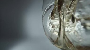 Bir bardağa dökülen beyaz şarabın yaratıcı makro yavaş çekim ham videosu. Doldurulmuş beyaz şaraplı bardaklar. Su ve kabarcıklarla yakın plan..