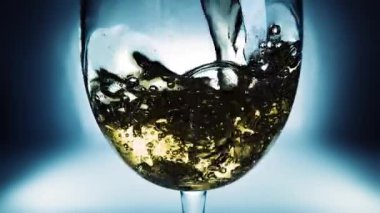 Bir bardağa dökülen beyaz şarabın yaratıcı makro yavaş çekim videosu. Doldurulmuş beyaz şaraplı bardaklar. Su ve kabarcıklarla yakın plan..