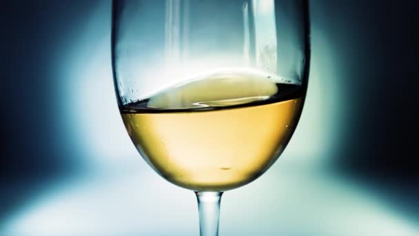 美しいカラフルなグラデーションの背景を持つ側面から側面にガラスに白ワインの創造的なマクロスローモーションビデオ波が飛び散っています スパークリングワインとガラスのクローズアップ — ストック動画