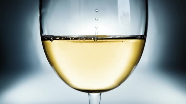 ガラスの白ワインの創造的なマクロスローモーションビデオとワインの落下低下 ゆっくりと落下するワインの滴が閉じられているガラス — ストック動画