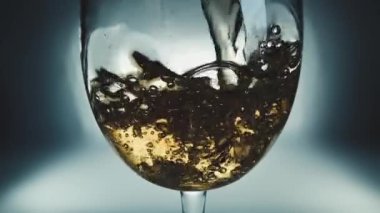 Bir bardağa dökülen beyaz şarabın yaratıcı makro yavaş çekim videosu. Doldurulmuş beyaz şaraplı bardaklar. Su ve kabarcıklarla yakın plan..