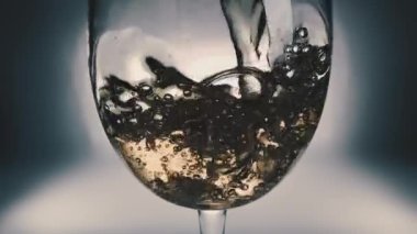 Bir bardağa dökülen beyaz şarabın yaratıcı makro yavaş çekim videosu. Doldurulmuş beyaz şarap bardağı. Eski grunge vintage tarzı.