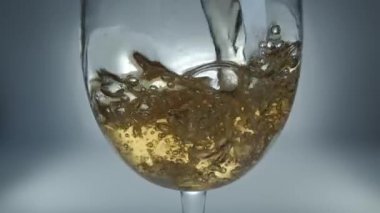 Bir bardağa dökülen beyaz şarabın yaratıcı makro yavaş çekim ham videosu. Doldurulmuş beyaz şaraplı bardaklar. Su ve kabarcıklarla yakın plan..