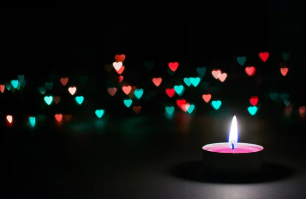 Candle on a black background with bokeh hearts — Stock Photo, Image