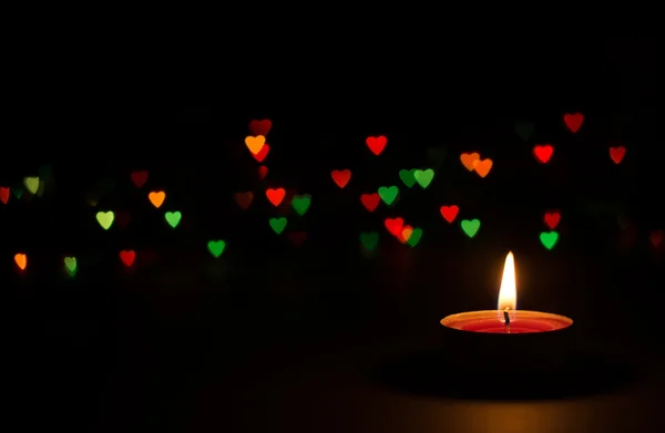 Candle on a black background with bokeh hearts — Stock Photo, Image