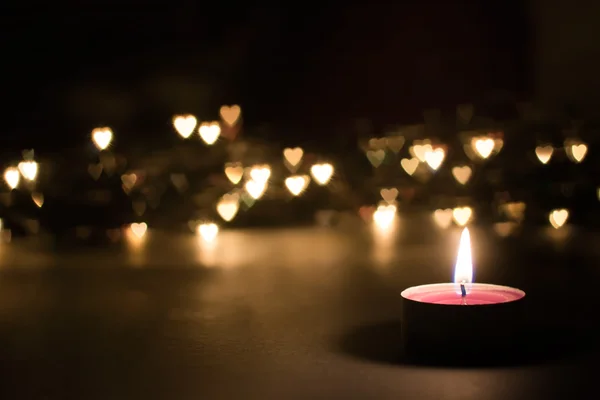 Candle on a black background with bokeh hearts Stock Photo