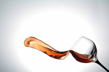 stream of wine being poured out off a glass isolated on a white background