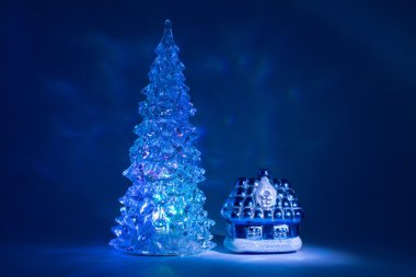 Toy Christmas tree shining with beautiful shadows Northern Lights near the house from a fairy tale