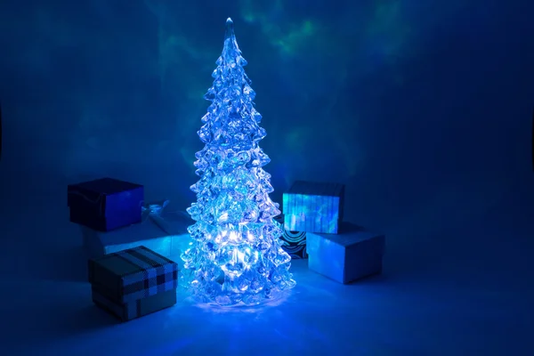 Weihnachtsbaum Spielzeug leuchtet mit einem schönen Schatten Nordlichter Hintergrund in der Nähe von Geschenkboxen und Highlights in Form von Sternen — Stockfoto