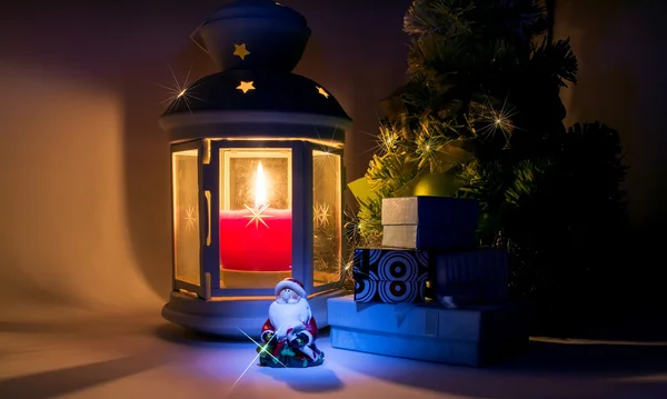 Lanterna com vela acesa e árvore de Natal com caixas de presente e Papai Noel com belas sombras e com um belo brilho como uma estrela — Fotografia de Stock