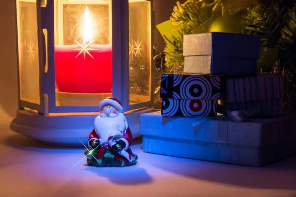 Lanterna com vela acesa e árvore de Natal com caixas de presente e Papai Noel com belas sombras e com um belo brilho como uma estrela — Fotografia de Stock