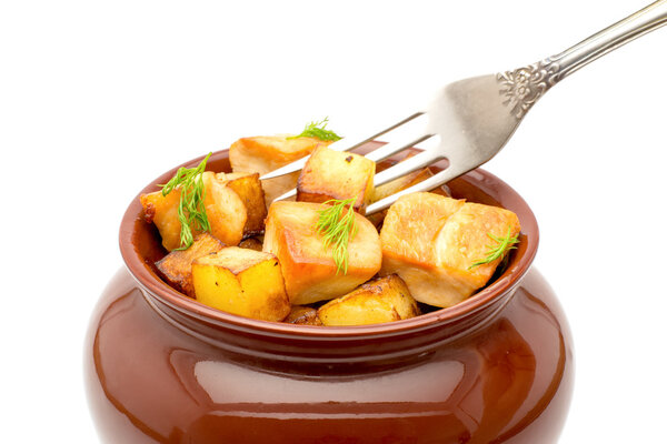 Fried potatoes with chunks of meat in a pot with a fork on a white background