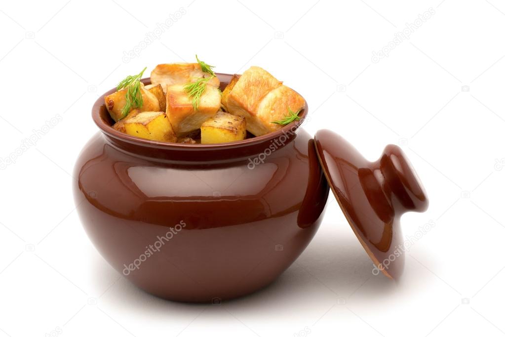 Fried potatoes with chunks of meat in a clay pot on a white back
