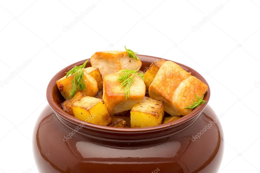 Fried potatoes with chunks of meat in a clay pot on a white background