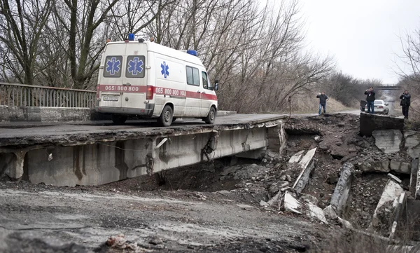 L'ambulanza attraversa il ponte che si è danneggiato dopo aver combattuto Foto Stock