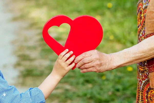 Barnbarn och mormor håller hjärtat i handen — Stockfoto