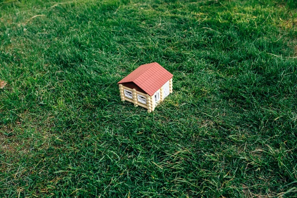 A casa de madeira de um log contra uma grama — Fotografia de Stock