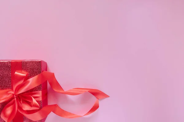 Czerwone pudełko z czerwoną wstążką i sercami na różowym tle na Walentynki. Miejsce na tekst. — Zdjęcie stockowe