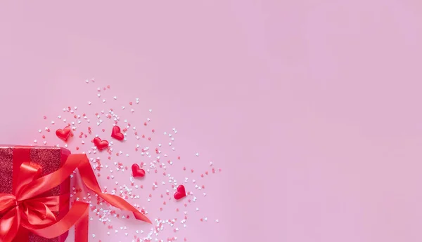 Caja roja de regalo con lazo rojo y corazones sobre fondo rosa para el día de San Valentín. Espacio para el texto. Banner ancho largo. — Foto de Stock