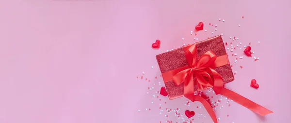 Czerwone pudełko z czerwoną wstążką i sercami na różowym tle na Walentynki. Miejsce na tekst. Długi sztandar szeroki. — Zdjęcie stockowe