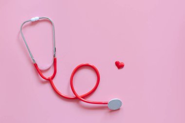 Yaratıcı tıbbi kartpostal steteskopu, pembe arka planda kırmızı kalp ve kırmızı var. Medicine Flatlay, hediye konsepti veriyor. Sevgililer Günü için arkaplan