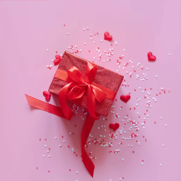 Czerwone pudełko z czerwoną wstążką i sercami na różowym tle na Walentynki. Miejsce na tekst. — Zdjęcie stockowe