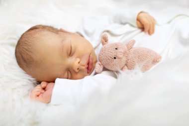 Beyaz yatak odasında bir haftalık sevimli bir bebek. Yeni doğmuş çocuk yatakta dinleniyor. Küçük çocuklar için çocuk odası. Çocuklar için tekstil ve yatak. Aile sabahı evde. Yaşam tarzı konsepti, gerçek hayat..