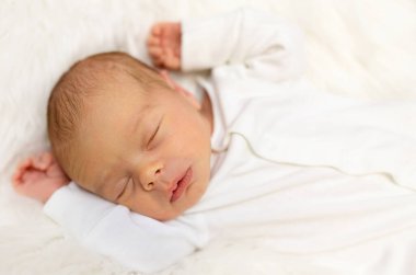 Beyaz yatak odasında bir haftalık sevimli bir bebek. Yeni doğmuş çocuk yatakta dinleniyor. Küçük çocuklar için çocuk odası. Çocuklar için tekstil ve yatak. Aile sabahı evde. Yaşam tarzı konsepti, gerçek hayat..