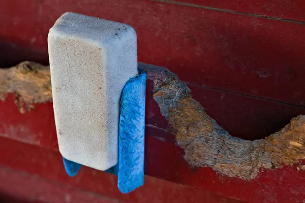 A used salt block for farm animals hung on a red barn wall. . High quality photo