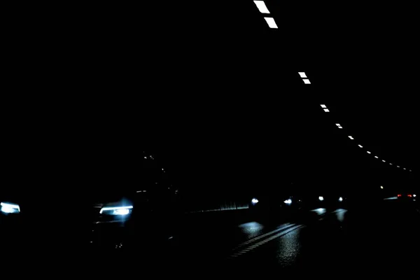 汽车在只有前灯和隧道照明显示的黑暗隧道内行驶 是的高质量的照片 — 图库照片